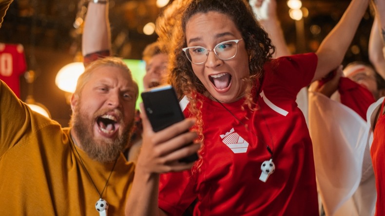 Female Football Fan Celebrating Holding Phone