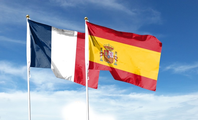 Flags of Spain and France Against Blue Cloudy Sky