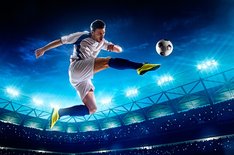 Football Player Kicking Ball in Stadium