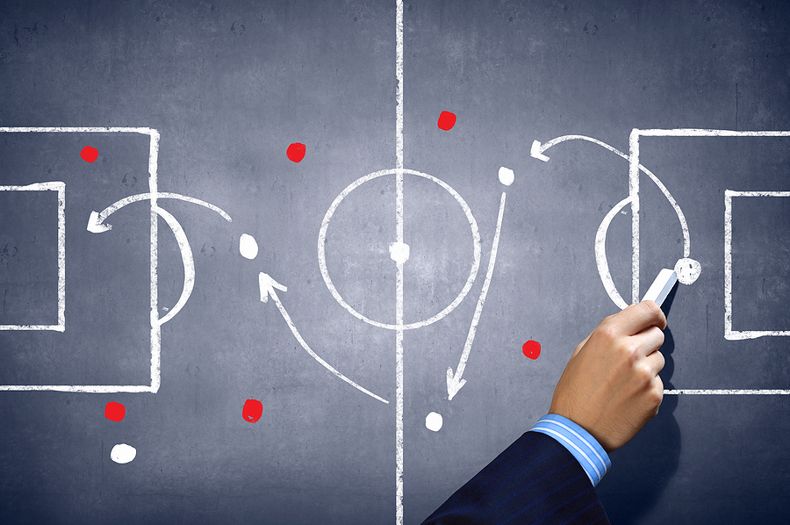 Football coach drawing strategy on chalkboard