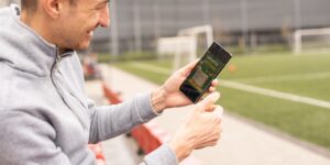 Man playing football themed slots on phone